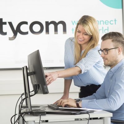 Citycom Mitarbeiterin, die ihrem Kollegen etwas auf dem Bildschirm zeigt